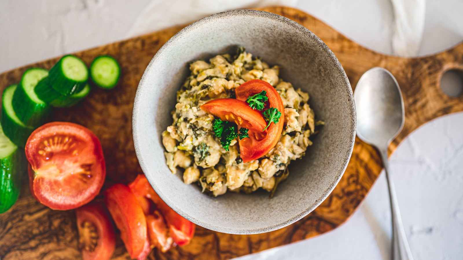 Insalata di ceci con pomodoro in una ciotola, con cetrioli e pomodori su un tagliere