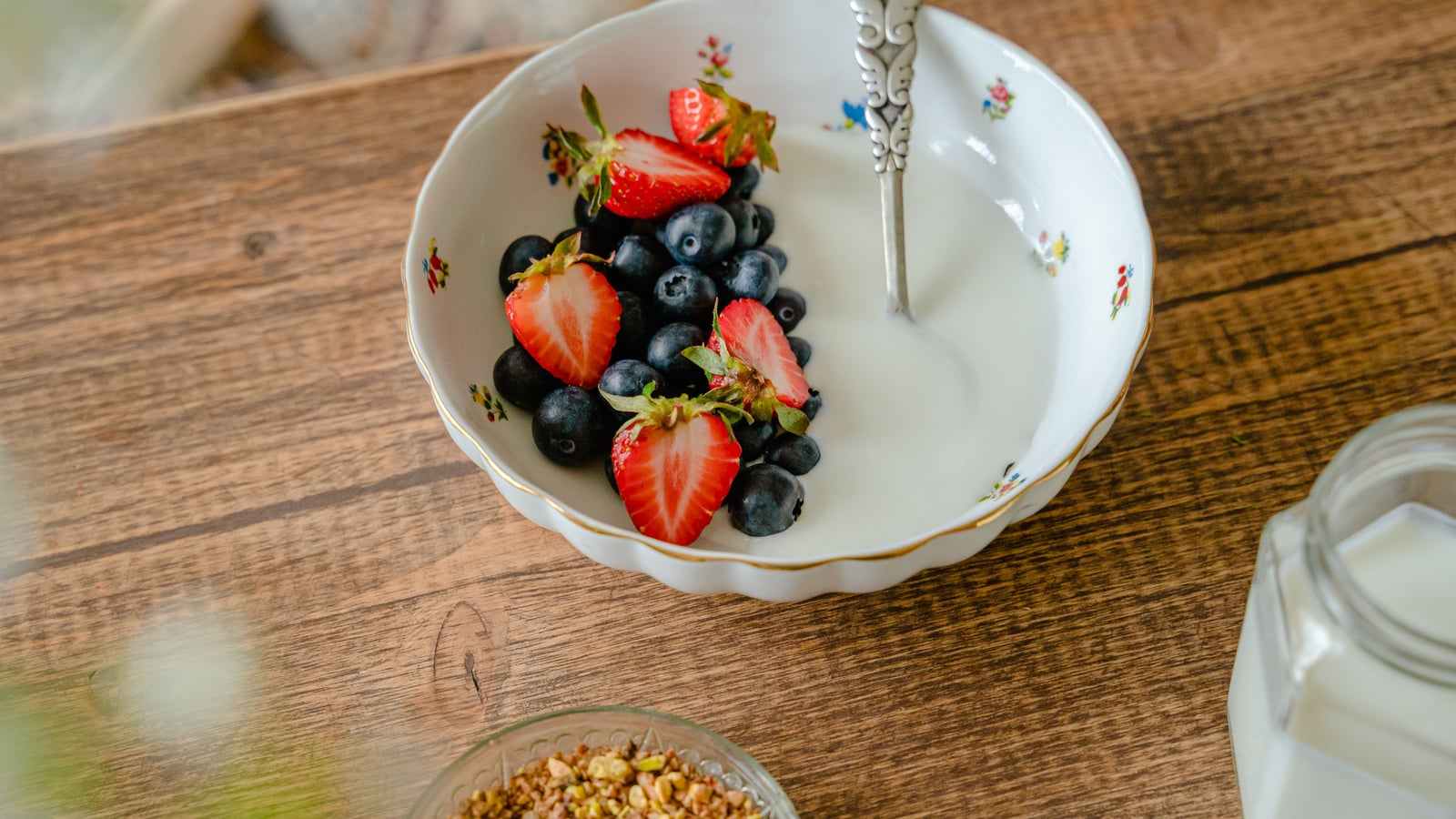 Una ciotola di yogurt con fragole e mirtilli su un tavolo di legno